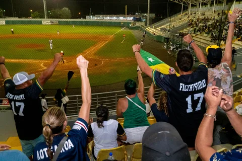 Fans in Filthy Friday jerseys cheering in the stands during a night baseball game