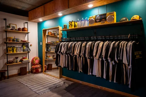T-shirts hanging on a rack and shelves with merch inside the shop
