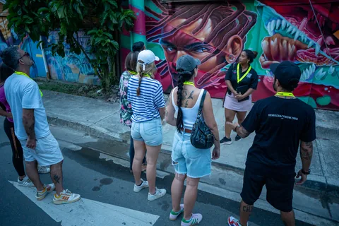 The walking tour group looking at a large street mural of a face