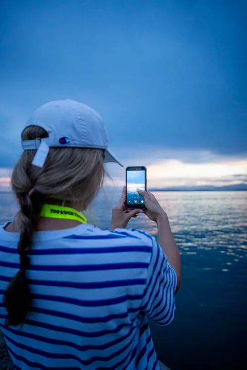 A tour guest taking a photo of the sea at sunset