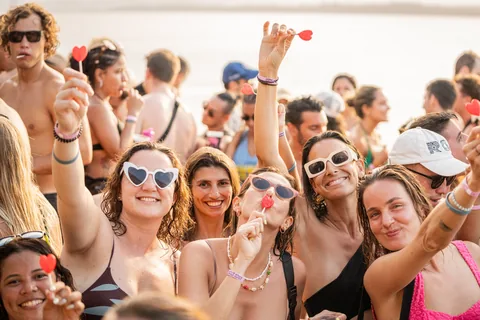 A crowd at Filthy Friday wearing heart-shaped sunglasses and holding lollipops