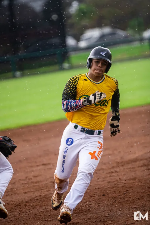 A Bocas player in a yellow jersey running the bases